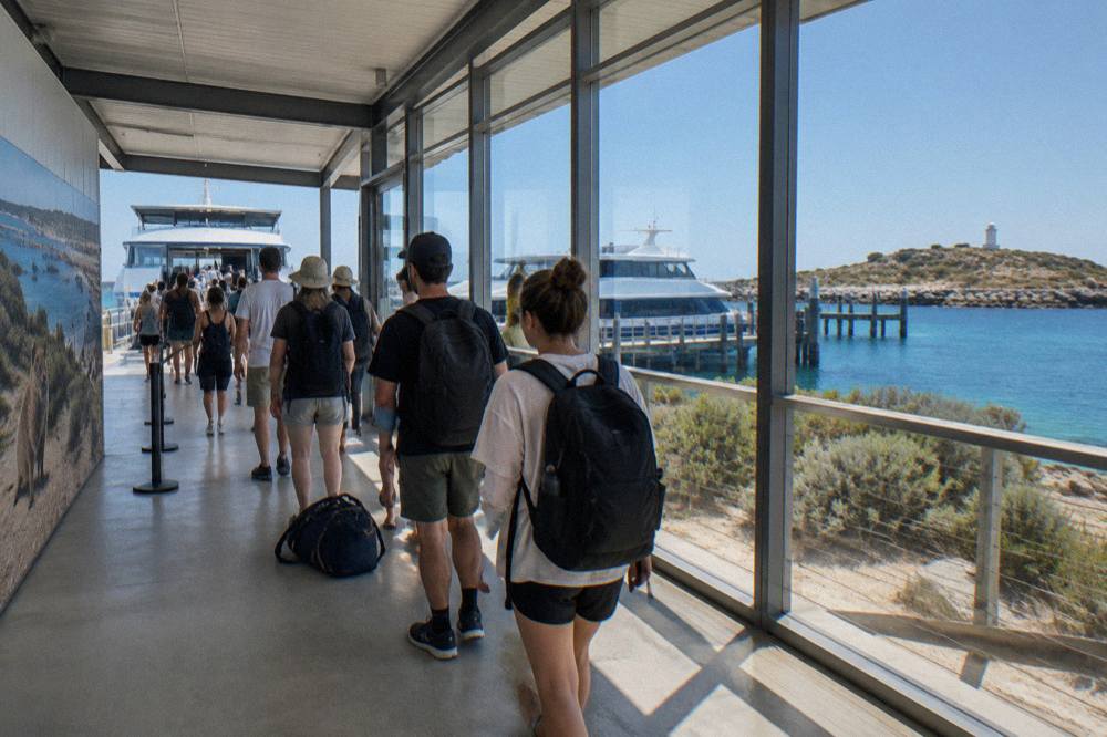 A queue of passengers with backpacks waiting at a ferry terminal gate