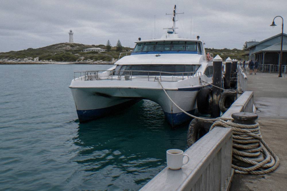 A passenger ferry moored at a city jetty on a river with buildings behind it