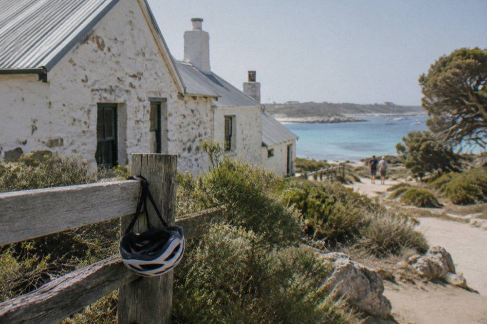 A bicycle leaning against a wooden fence near the Thomson Bay settlement with heritage stone buildings behind