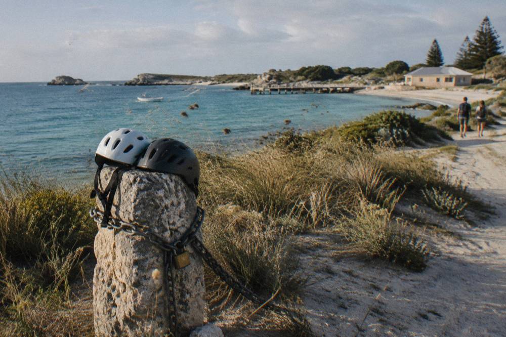 Bicycles parked on a sandy track overlooking a calm blue bay