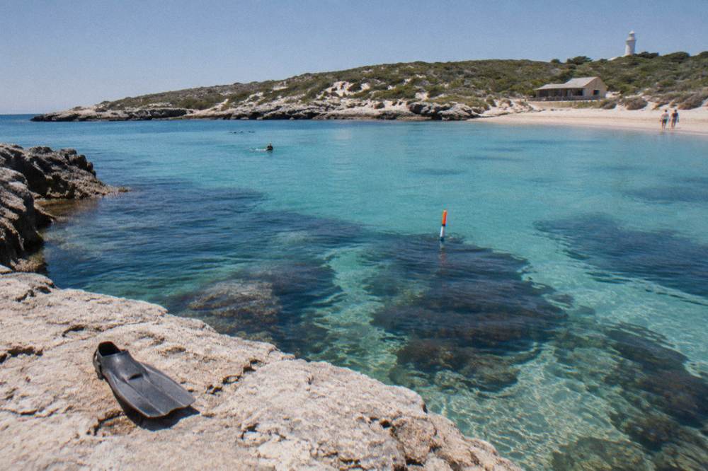 Turquoise shallows over reef with snorkel trail marker visible above the water