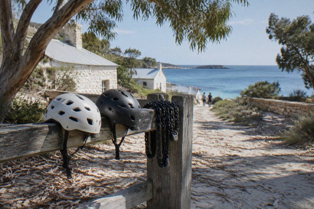 Bicycles leaning against a wooden fence near the Thomson Bay settlement with the sea behind