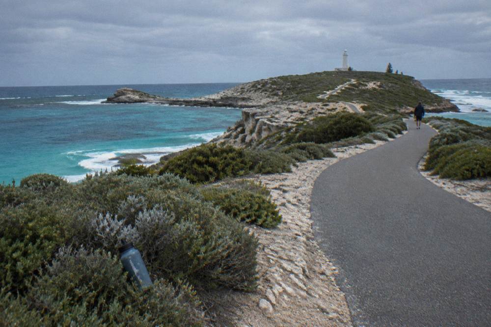 A coastal cycling path curving along a Rottnest headland with turquoise water on both sides