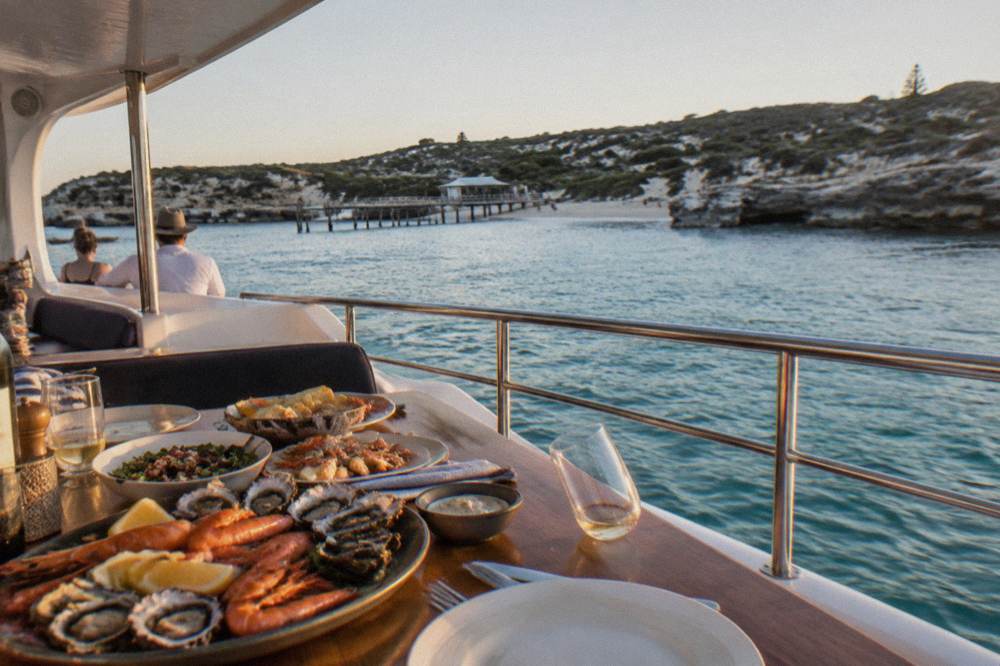 A long table set for a seafood lunch on the deck of a boat in a sheltered bay