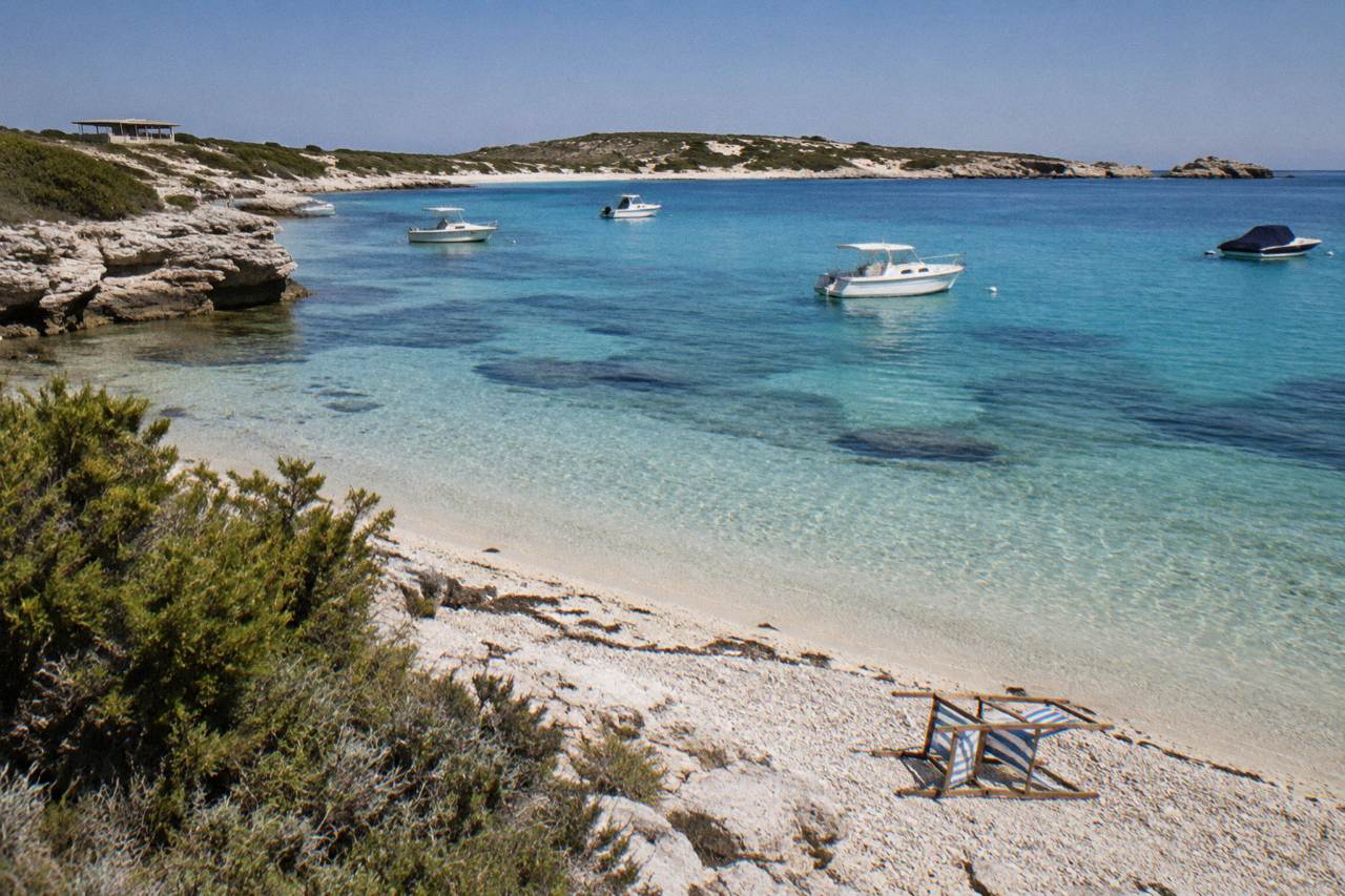 Turquoise water and sandy beach at Rottnest Island with anchored boats in the bay