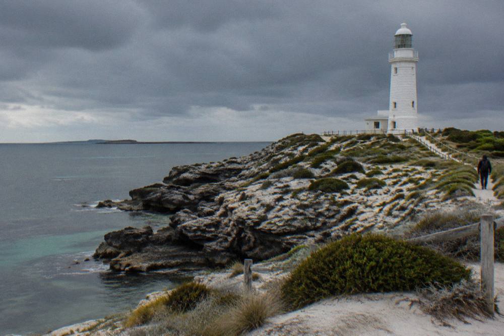 Dark rain clouds passing over calm turquoise water and rocky coastline at Rottnest Island