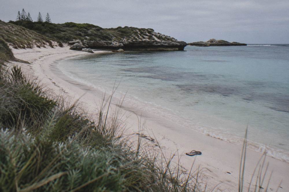 An empty sandy beach and calm bay at Rottnest Island on an overcast morning