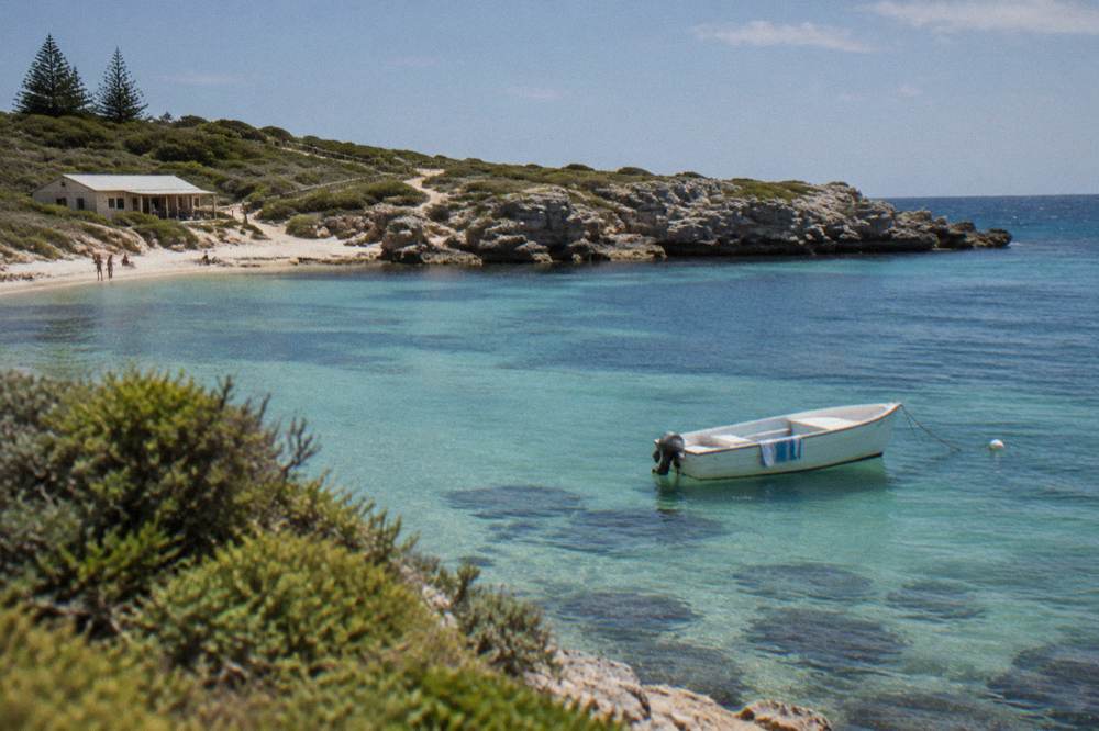 A sheltered turquoise bay with calm water and rocky headlands on the horizon