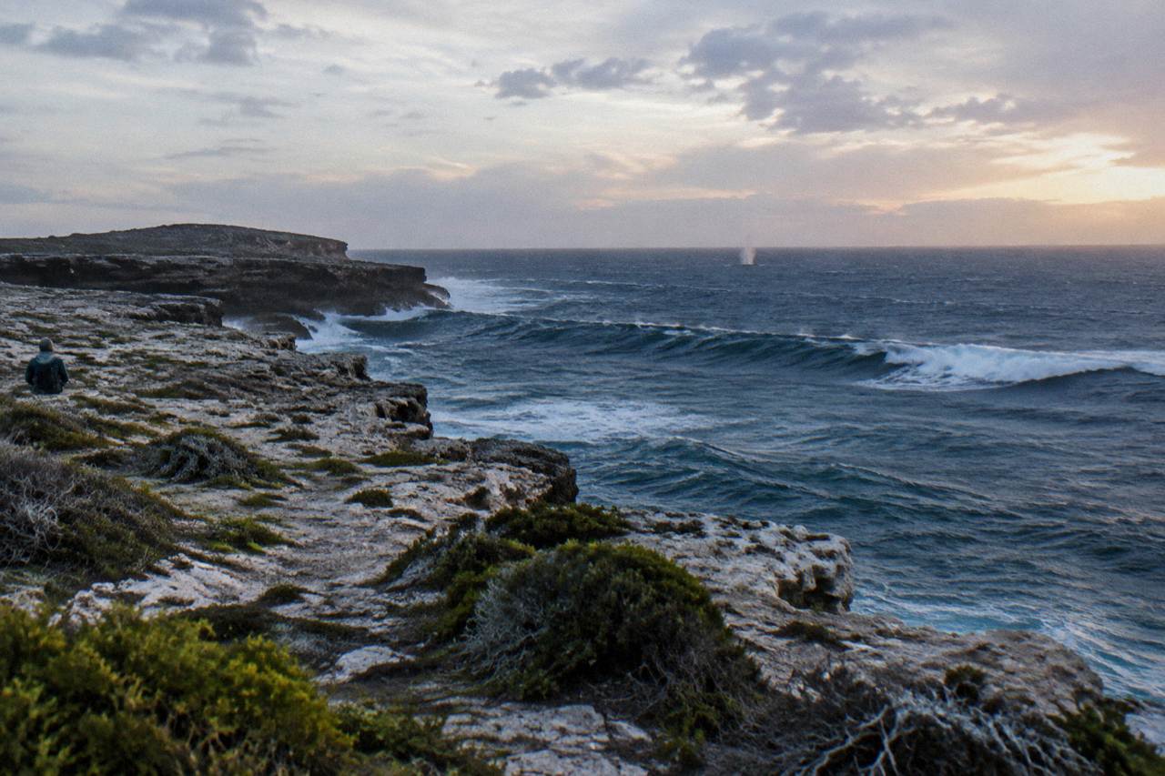 Open ocean swell beyond a rocky island headland under a wide sky
