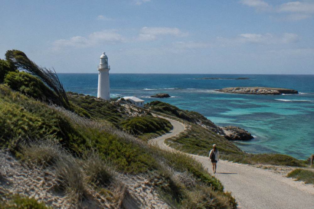 A winding road on Rottnest Island with coastal heath and turquoise water beyond