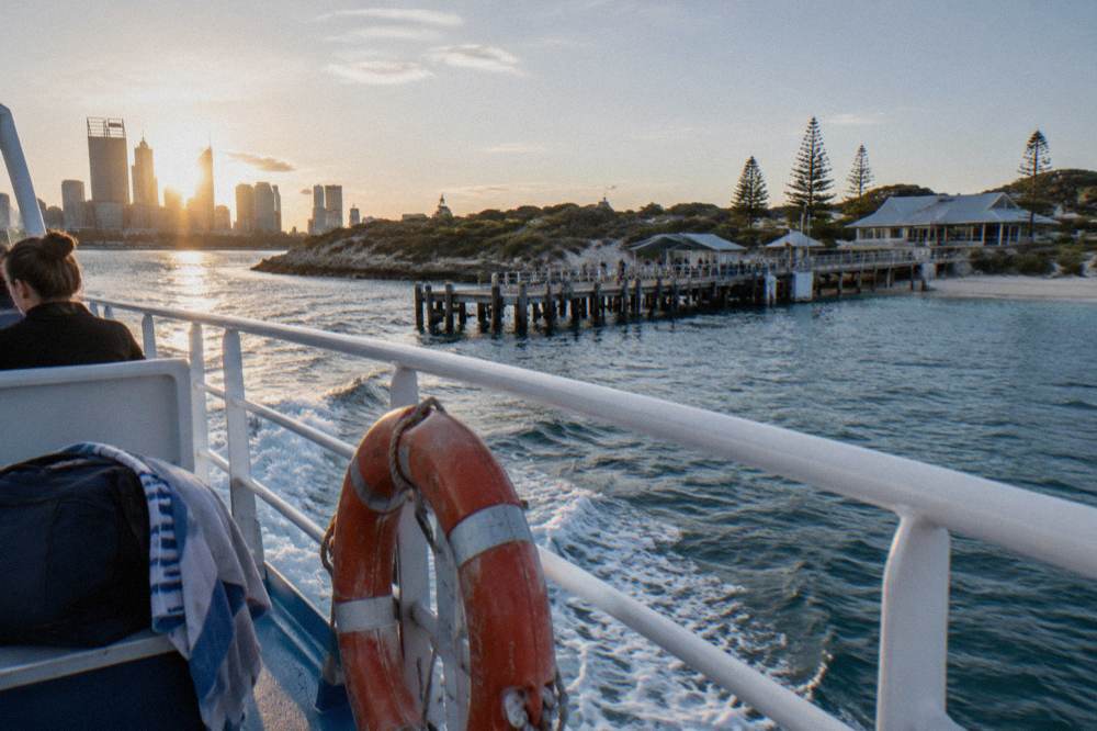 A boat cruising along the Swan River with city buildings in the distance