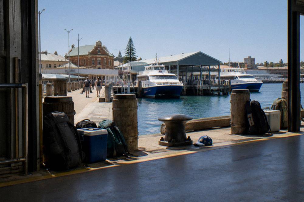 Queue of passengers with backpacks waiting at a ferry terminal gate in warm morning light