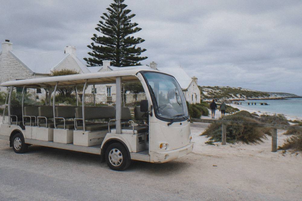 A small open-sided shuttle bus at a stopping bay near the Thomson Bay settlement