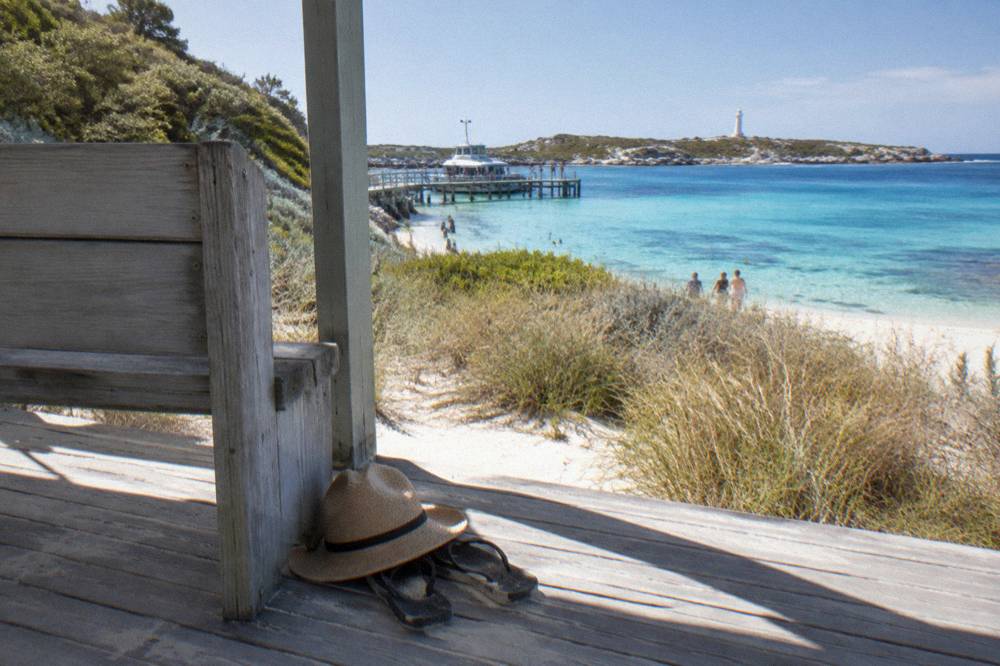 A sheltered ferry waiting area beside turquoise water at a Rottnest Island jetty on a bright morning