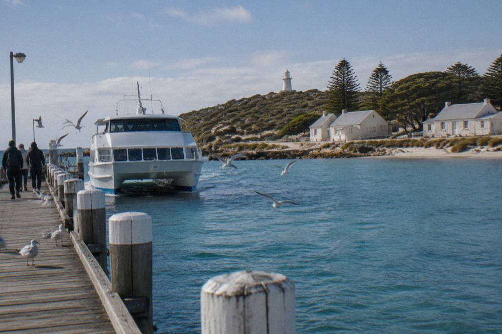 A ferry approaching the main jetty at Thomson Bay with white buildings of the settlement behind