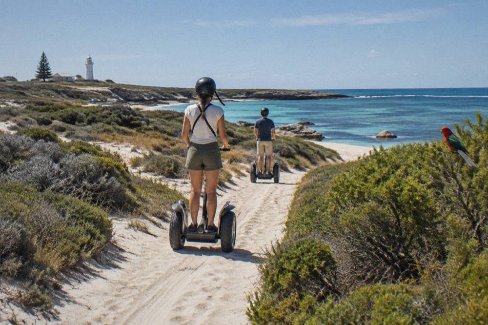 A guided segway group riding single file along a coastal path lined with low scrub