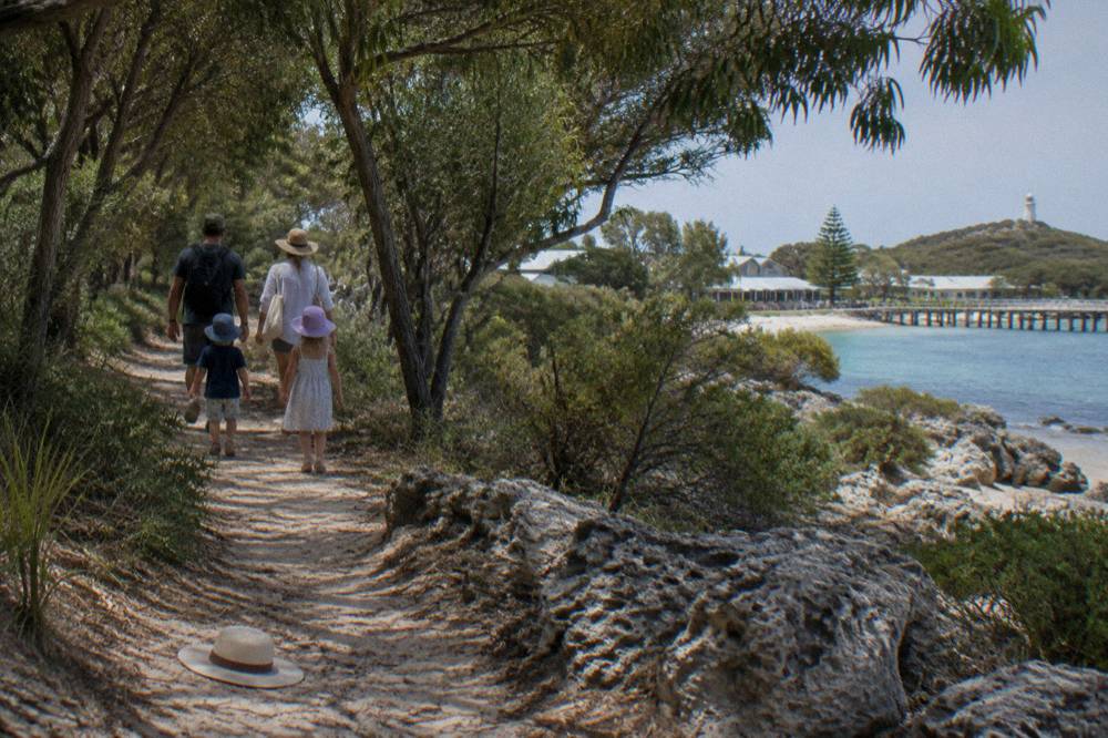 A family with young children walking a flat shaded path near the Thomson Bay settlement