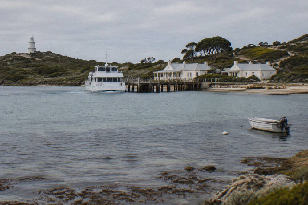 A ferry approaching an island jetty across calm blue water.