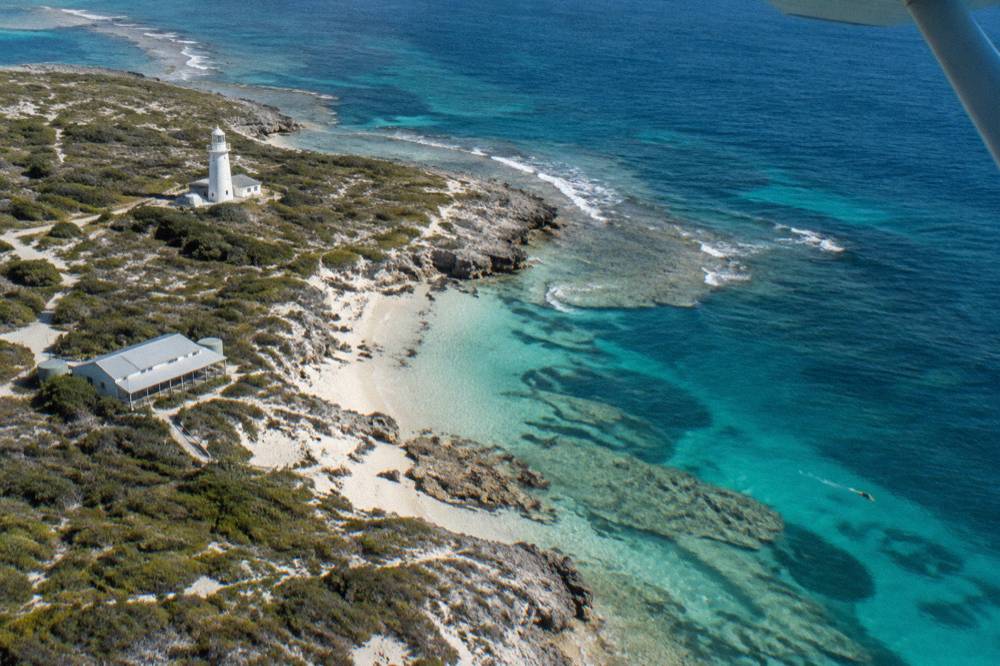 A high wing view of reefs and turquoise water around an island coastline