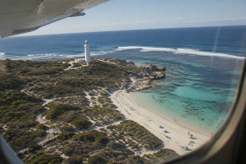 A light aircraft window view along a coastline with white surf lines and bays