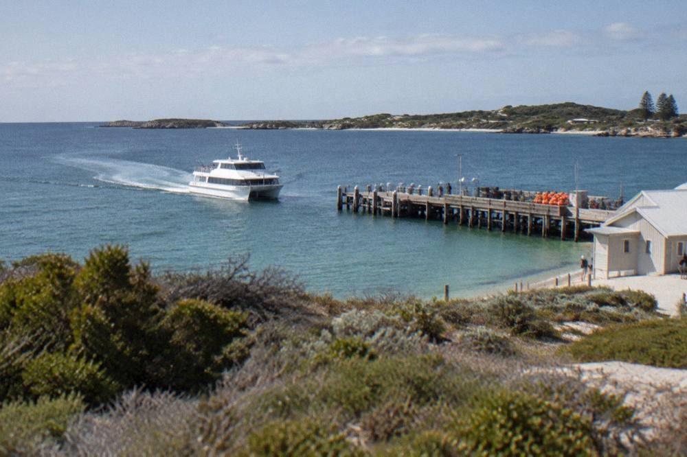A ferry approaching a jetty across open water toward an island shoreline