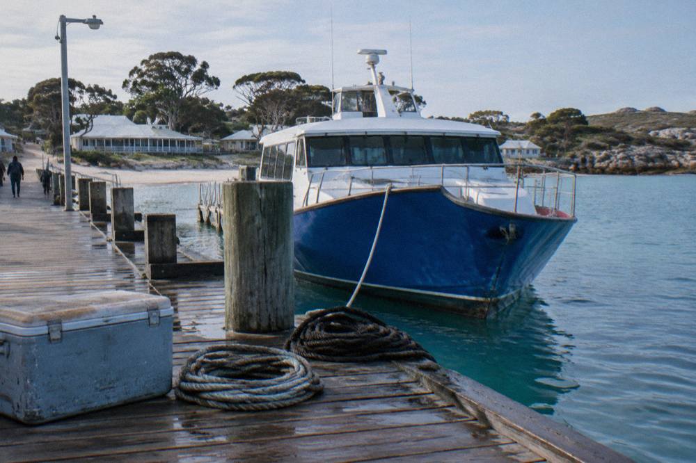 Blue ferry moored at the main jetty in Thomson Bay with the settlement buildings behind