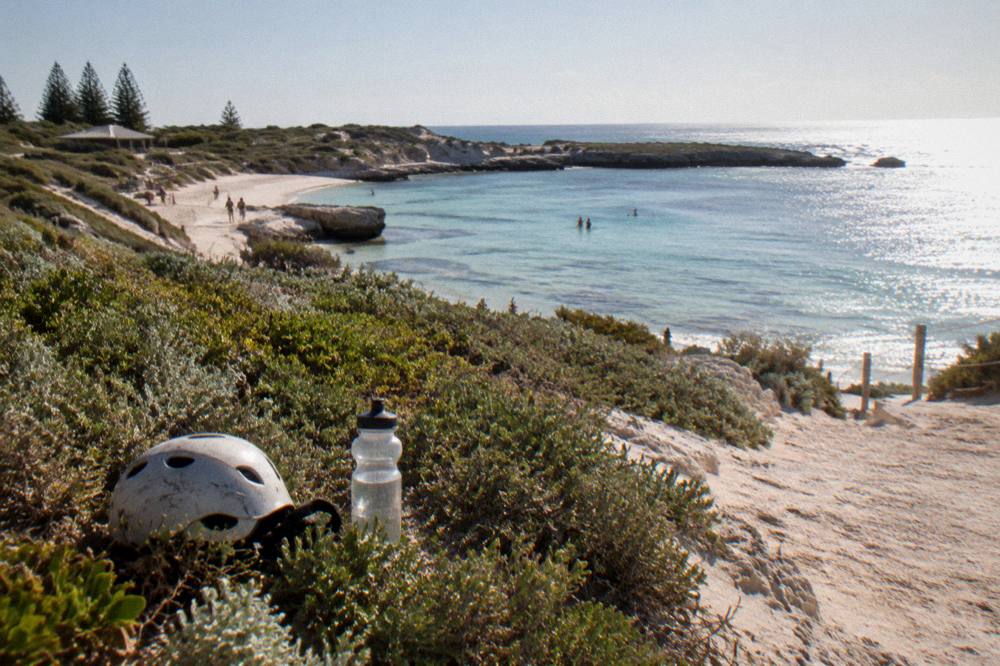 Visitors cycling along a coastal path with white sand and clear water on Rottnest Island