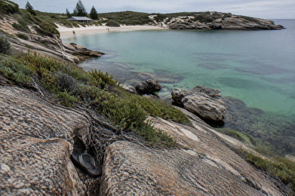 Granite coastline and low coastal scrub above calm water at Wadjemup