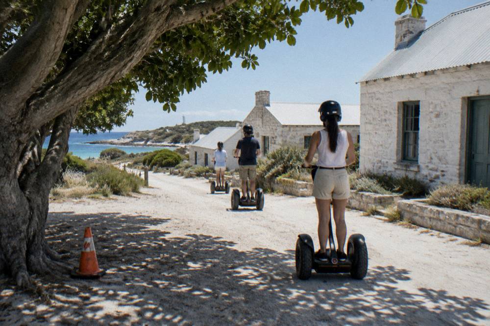 A guided tour group on segways moving along a heritage street near the Thomson Bay settlement